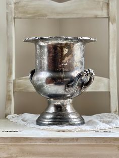 a silver vase sitting on top of a wooden table