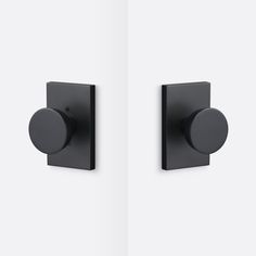 two black square knobs on the side of a white wall and one has a round button