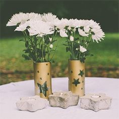 two vases with white flowers in them sitting on a table next to some rocks