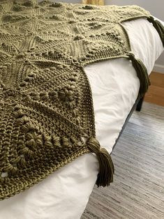 a crocheted blanket with tassels on top of a bed in a bedroom