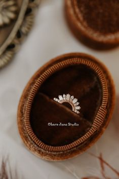 a diamond ring sits in an open wooden box on a white tablecloth with other jewelry items