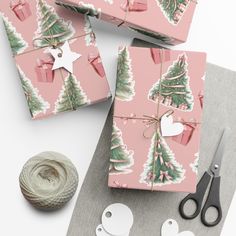 pink wrapping paper with christmas trees on it next to scissors, yarn and twine