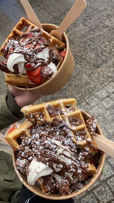 two waffles with chocolate and strawberries in them are being held by someone