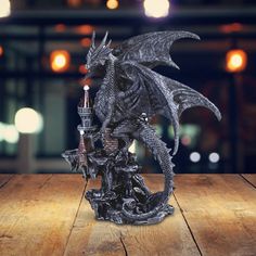 a black dragon figurine sitting on top of a wooden table with lights in the background