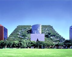 a large building with many windows and plants growing on it's side in front of other buildings