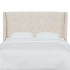 an upholstered headboard with white linens and pillows on a plain bed