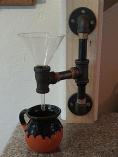 an orange and black vase sitting on top of a counter next to a faucet