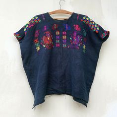 an embroidered top hanging on a white wall