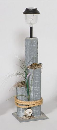 a light that is sitting on top of a wooden post with some plants in it