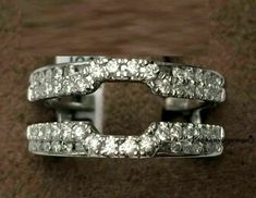 two white gold rings with diamonds on top and bottom, sitting on a brown carpet