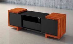 a black and wood entertainment center with two drawers on each side, in front of a concrete wall