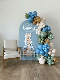 a chair and balloon arch in front of a wall with an image of a bunny on it