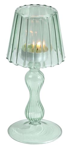 a glass table lamp with a lit candle in the middle on top of it's base