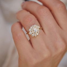 a woman's hand with a diamond ring on top of her finger and an engagement ring in the middle