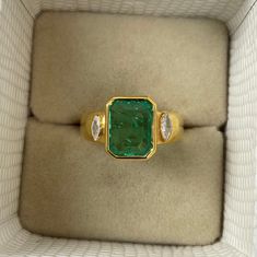 an emerald and diamond ring in a box