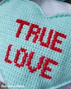 a crocheted heart with the words true love written on it in red and blue