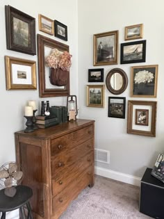 a dresser with many framed pictures on the wall