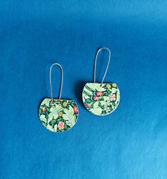 pair of earrings on blue background with floral print and metal earwires, top view