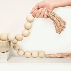 a wooden bead necklace being held by a person's hand over a box