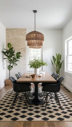 a dining room table with black chairs and a potted plant in the center on top