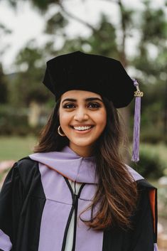 a woman in a graduation gown and cap smiles at the camera while wearing a tassel