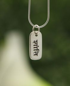 Shanti translates to “peace,” referring to the inner peace we cultivate so that we remain strong during difficult times. Take strength from this simple engraved pendant of sterling silver. Wear as is or pair with other pendants to make an inspirational accessory that’s personal to you. Tag style necklace pendant Engraved with “Shanti” Sanskrit inscription on reverse side Made of sterling silver Pendant measures ¾ x 3/8 inches Made in India This item may features slight variations in overall appe Shanti Sanskrit, Shiva Pendant, Buddhist Necklace, Buddha Necklace, Bar Pendant Necklace, Engraved Pendant, Jewelry Care Instructions, Unique Holiday Gifts, Difficult Times