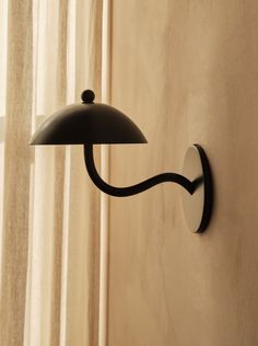 a wall light that is on the side of a wall with curtains in the background