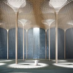 a person sitting in the middle of a room filled with columns and arches on either side