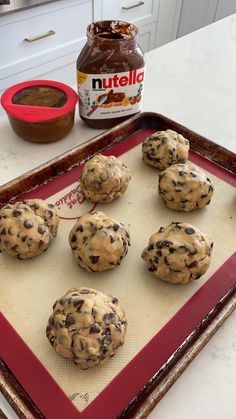 chocolate chip cookies on a baking sheet with peanut butter and nutella in the background