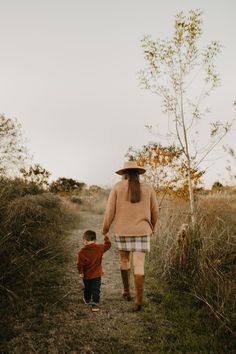 a woman and child walking down a dirt road