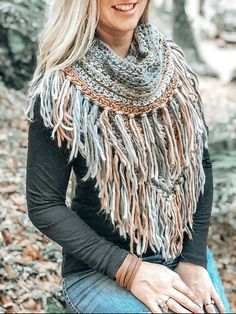 a woman sitting on the ground with her hands in her pockets and wearing a scarf