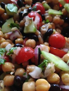 a salad with beans, cucumbers, tomatoes and lettuce on it