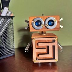 a wooden toy with two eyes on top of a table next to a pen holder