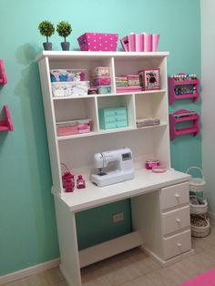 a sewing machine sitting on top of a white desk next to a shelf filled with craft supplies