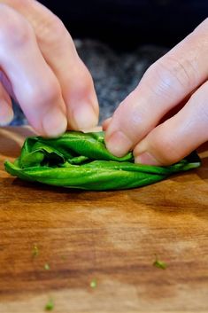 a person cutting up some green peppers on a wooden board