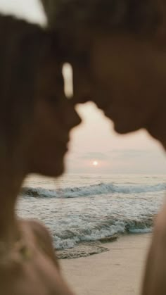 two people standing next to each other near the ocean