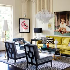 a living room with yellow couches and black chairs in front of a painting on the wall