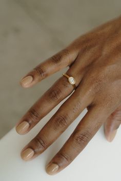 a person's hand with a diamond ring on top of their left hand, resting on a white surface