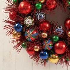 a christmas wreath with red, green and gold ornaments on white wooden background ornament