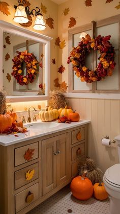 a bathroom decorated for fall with wreaths and pumpkins on the sink counter top