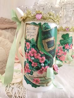 two decorated vases sitting on top of a lace tablecloth covered table cloth with ribbons around them