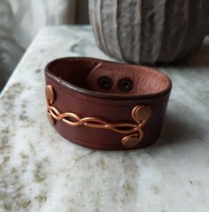 Rugged Men's Leather Bracelet. One of a kind. Made from full grain hand dyed veg tan leather with hammered copper design on front. MADE IN USA. Double snap closure on back. 8" long x 1.5 " wide. Perfect guy gift for any occasion. Can be personalized with initials. Handmade Vintage Brown Leather Bracelet Gift, Rustic Hand Tooled Adjustable Bracelets, Brown Handmade Cuff Bracelets, Handmade Brown Cuff Bracelets, Handmade Adjustable Vintage Brown Jewelry, Unique Brown Cuff Bracelets, Brown Copper Cuff Bracelet As Gift, Handmade Rustic Cuff Bracelet, Rustic Handmade Cuff Bracelets