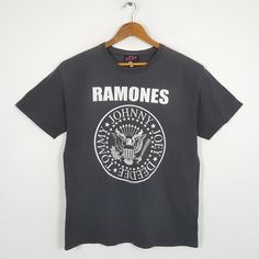 a black ramons t - shirt hanging on a wooden hanger against a white wall