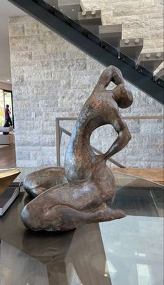 a statue sitting on top of a glass table next to a stair case in a building