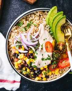 a bowl filled with rice, beans, avocado, tomatoes and other vegetables