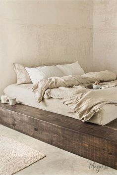 an unmade bed sitting in a bedroom next to a window with white walls and flooring