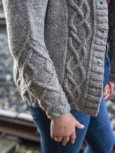 a close up of a person wearing a sweater and holding the hand of another person