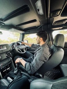 a man sitting in the driver's seat of a truck with his hands on the steering wheel