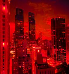 the city skyline is lit up in red and orange lights at night time, with skyscrapers visible