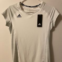 Adidas Volleyball Comfy Short Sleeve Shirt. 89% Polyester, 11% Spandex. White V-neck Athleisure Activewear, White Adidas Sporty T-shirt, Adidas White Sporty T-shirt, White Stretch Tennis Tops, White Stretch Tops For Tennis, White Adidas T-shirt With Moisture-wicking, Adidas Moisture-wicking Sports Tops, Adidas Sports Tops With Go-dry Technology, Adidas Go-dry Sports Tops